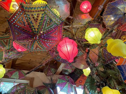 Colorful umbrellas and lanterns hang from a wooden ceiling, creating a vibrant and festive atmosphere.
