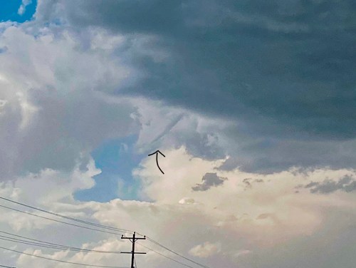 A cloudy sky with a hint of blue peeking through, featuring a distinct cloud formation pointing upwards.