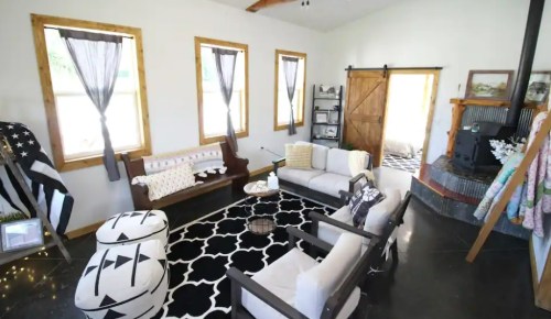 Cozy living room with a black and white rug, comfortable seating, and large windows letting in natural light.