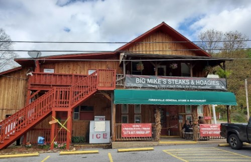 A rustic wooden building with a sign for "Big Mike's Steaks & Hoagies" and a staircase leading to the upper level.