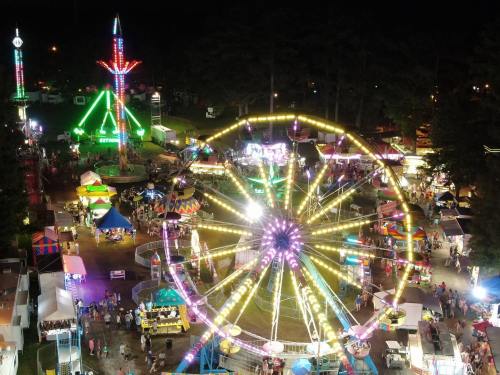 A vibrant night scene of a carnival with colorful lights, rides, and crowds enjoying various attractions.