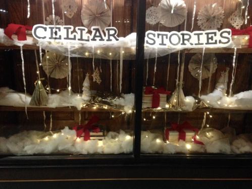A festive display with "CELLAR STORIES" sign, decorated with lights, gifts, and winter-themed decor.
