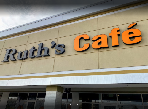 Sign for "Ruth's Café" with orange lettering on a beige building exterior.
