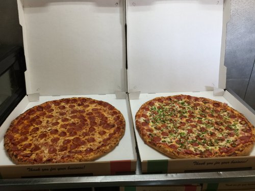 Two large pizzas in open boxes: one with pepperoni and cheese, the other with green peppers and sausage.