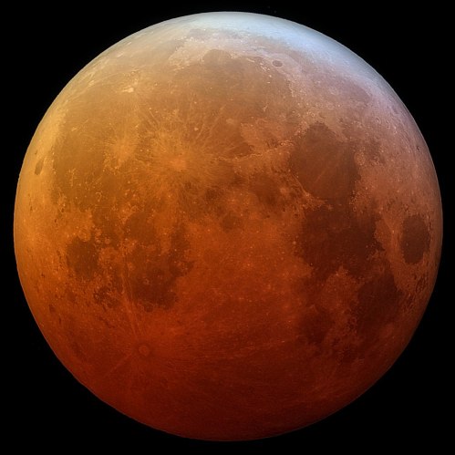 A close-up view of the Moon, showcasing its surface features with a reddish hue.