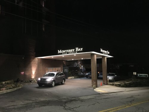Nighttime view of Monterrey Bay Fish Grotto entrance, featuring illuminated signage and parked cars.