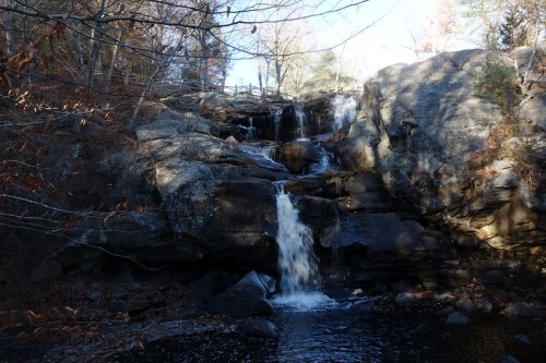 A serene waterfall cascading over rocky terrain, surrounded by trees in a tranquil natural setting.
