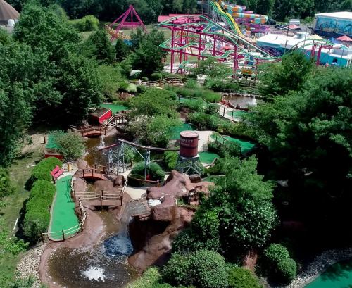 Aerial view of a vibrant amusement park featuring rides, mini-golf, and lush greenery.