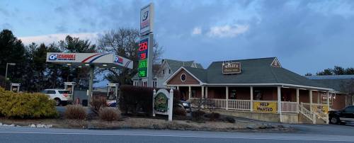 A gas station and restaurant building with a "Help Wanted" sign, set against a cloudy sky.