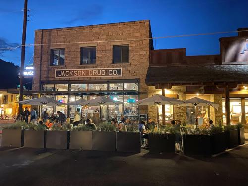 Outdoor dining area at Jackson Drug Co. with patrons under umbrellas, illuminated by evening lights.