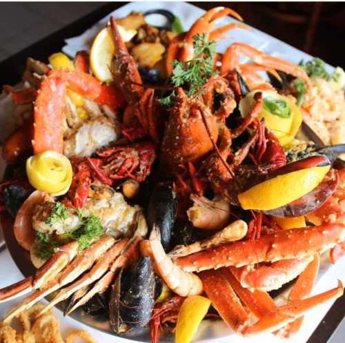 A vibrant seafood platter featuring lobster, crab, shrimp, mussels, and garnished with lemon and herbs.
