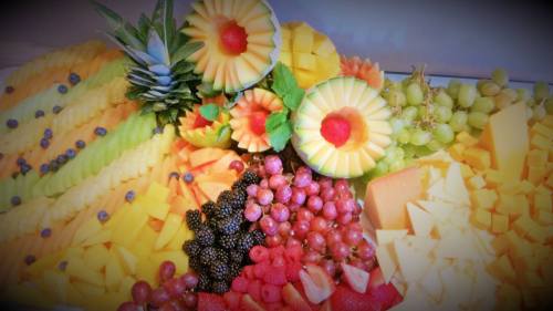 A colorful assortment of sliced fruits, including melons, grapes, berries, and pineapple, arranged artistically.