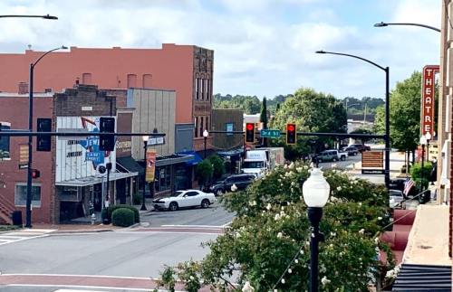 A street view of a small town with shops, traffic lights, and a theater sign on a clear day.