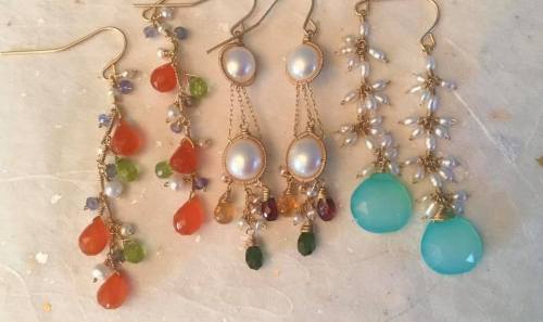 A collection of five pairs of elegant earrings featuring colorful gemstones and pearls on gold hooks.