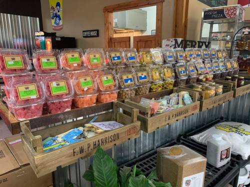 A display of colorful packaged snacks and treats in a rustic wooden stand at a market.