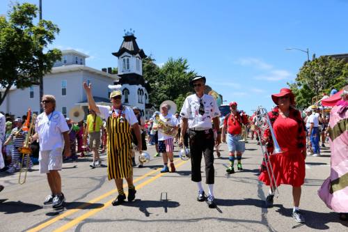 A lively parade scene with participants in colorful costumes marching down a sunny street.