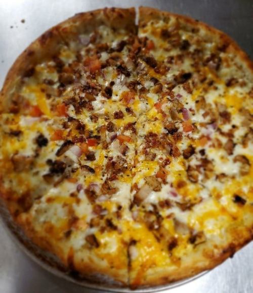 A freshly baked pizza topped with cheese, diced tomatoes, and crispy bacon, sliced into eight pieces.