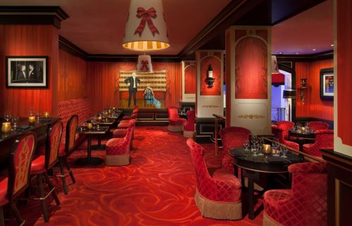 Cozy restaurant interior with red walls, plush seating, and elegant decor, featuring tables set for dining.