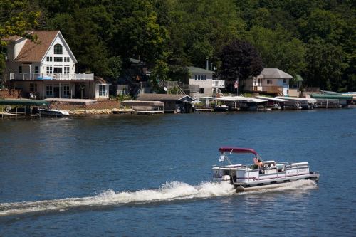 A boat glides across a calm lake near waterfront homes surrounded by lush greenery.