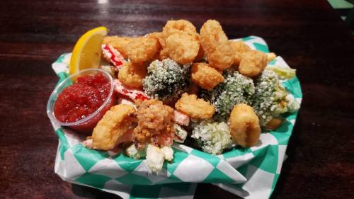 A colorful platter of fried seafood and vegetables, served with a lemon wedge and a side of marinara sauce.