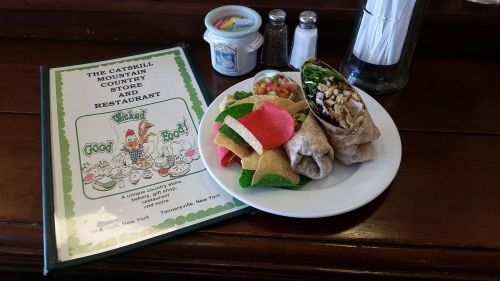 A plate with a wrap, colorful tortilla chips, and a menu for The Catskill Mountain Country Store and Restaurant.
