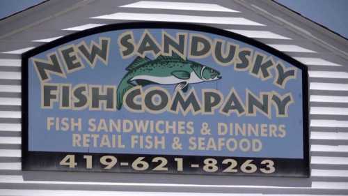 Sign for New Sandusky Fish Company featuring fish sandwiches, dinners, and retail fish & seafood. Phone number included.