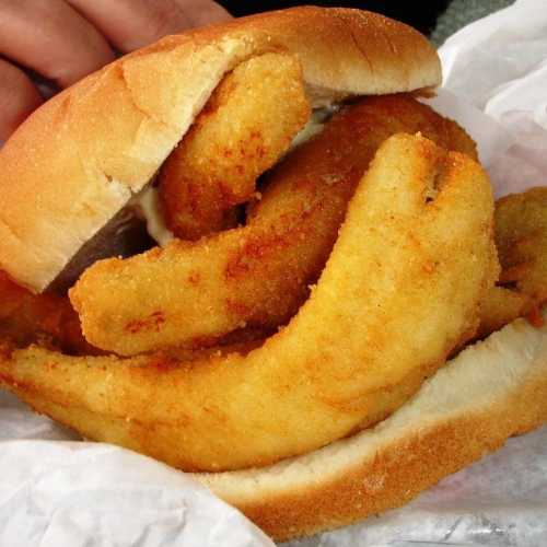 A close-up of a sandwich filled with golden, fried fish fillets, resting in a soft bun.