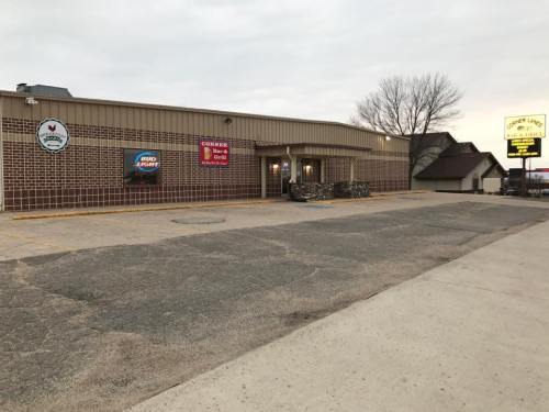 Exterior view of a restaurant with a brick facade, signage, and a parking lot under a cloudy sky.