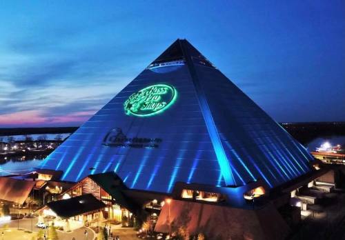 A large pyramid-shaped building illuminated at dusk, featuring a glowing sign for "Bass Pro Shops."