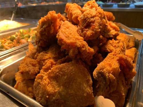A large pile of golden-brown fried chicken pieces in a serving tray.