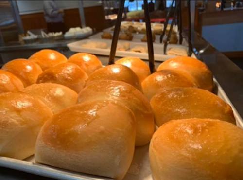 A tray of freshly baked, golden-brown dinner rolls arranged neatly.