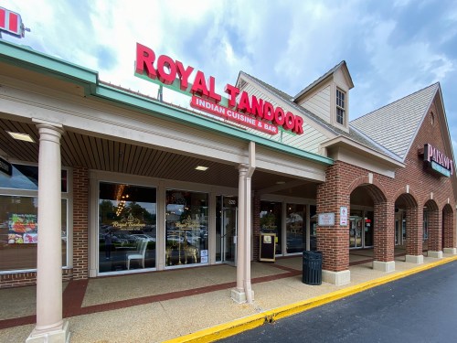 Exterior of Royal Tandoor Indian Cuisine & Bar, featuring a red sign and a brick facade in a shopping plaza.
