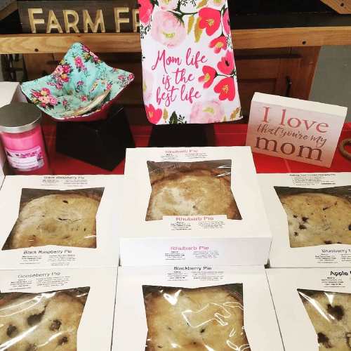 A display of various pies in boxes, candles, and decorative signs celebrating motherhood and family.