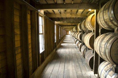 A wooden corridor lined with barrels, illuminated by natural light from windows.