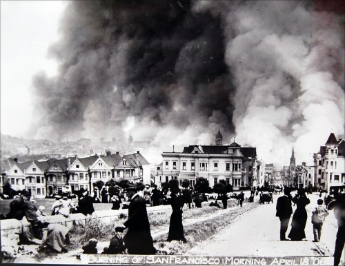 Historic photo of the 1906 San Francisco earthquake aftermath, with smoke rising and people gathered in the foreground.