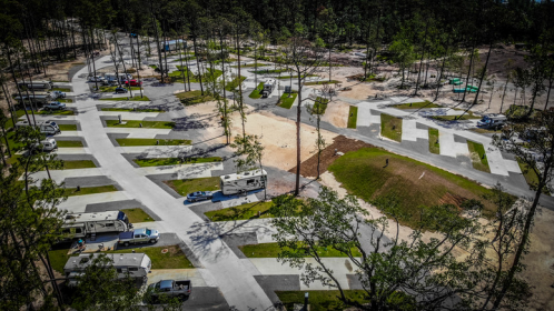 Aerial view of a campground with RVs parked along winding roads amidst trees and open spaces.