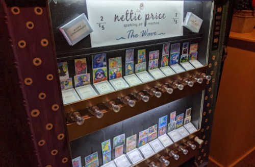 A vintage vending machine displaying colorful art pieces for sale, labeled "Nettie Price Sparkling Art Machine."