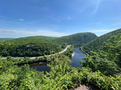 A scenic view of a winding river surrounded by lush green hills under a clear blue sky.