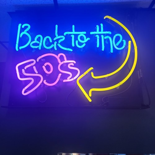 Neon sign reading "Back to the 50's" with an arrow, glowing in vibrant blue and yellow colors.
