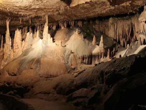 Stalactites and stalagmites in a dimly lit cave, showcasing unique rock formations and textures.