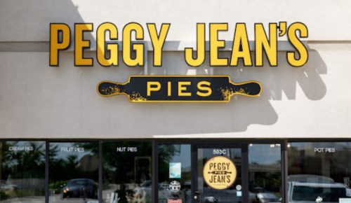 Sign for Peggy Jean's Pies, featuring the name prominently with a rolling pin graphic, in front of a storefront.