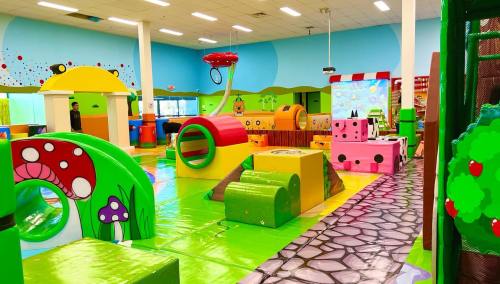 Colorful indoor play area with various soft play structures, including tunnels, slides, and themed decorations.