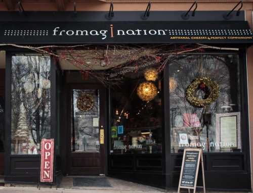 A storefront with a sign reading "fromag!nation," featuring holiday decorations and an "Open" sign.