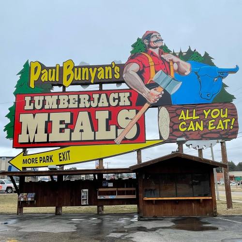 Colorful sign for "Paul Bunyan's Lumberjack Meals" featuring a lumberjack with an axe, promoting all-you-can-eat meals.