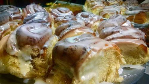 Close-up of freshly baked cinnamon rolls drizzled with creamy icing, showcasing their soft, fluffy texture.