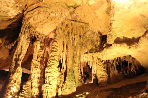 Stalactites and stalagmites in a dimly lit cave, showcasing intricate rock formations and textures.