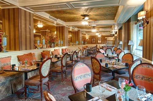 Elegant restaurant interior with patterned chairs, tables set for dining, and decorative floral arrangements.