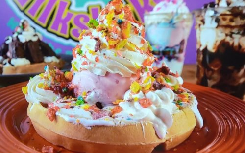 A colorful dessert featuring a waffle topped with whipped cream, ice cream, and sprinkles, served on a vibrant plate.