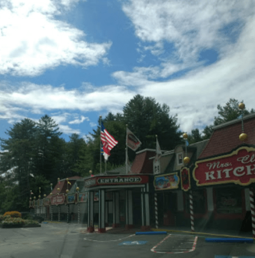 A colorful restaurant with a sign reading "Mrs. W's Kitchen," surrounded by trees and a blue sky with clouds.