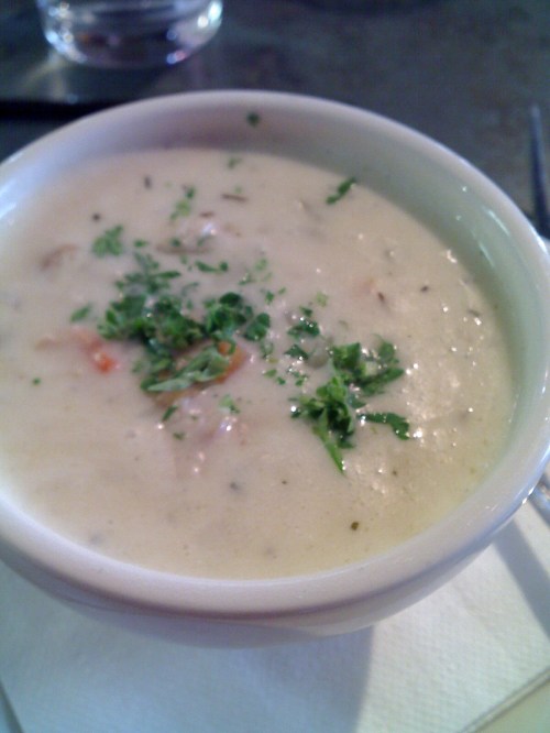 A bowl of creamy soup garnished with chopped herbs, served on a napkin.